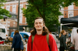 Young man with long hair wearing a red jumper and a backpack