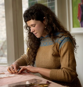 young woman with long dark hair working on a clothing pattern