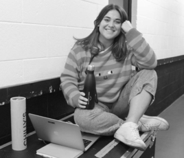 black and white photo of young woman sitting on a bench with crossed legs