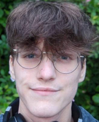 colour photo of young man's head, white skin, brown hair, long fringe, specatacles